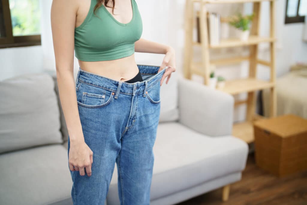 Asian woman dieting Weight loss. Slim woman in oversize jeansÂ